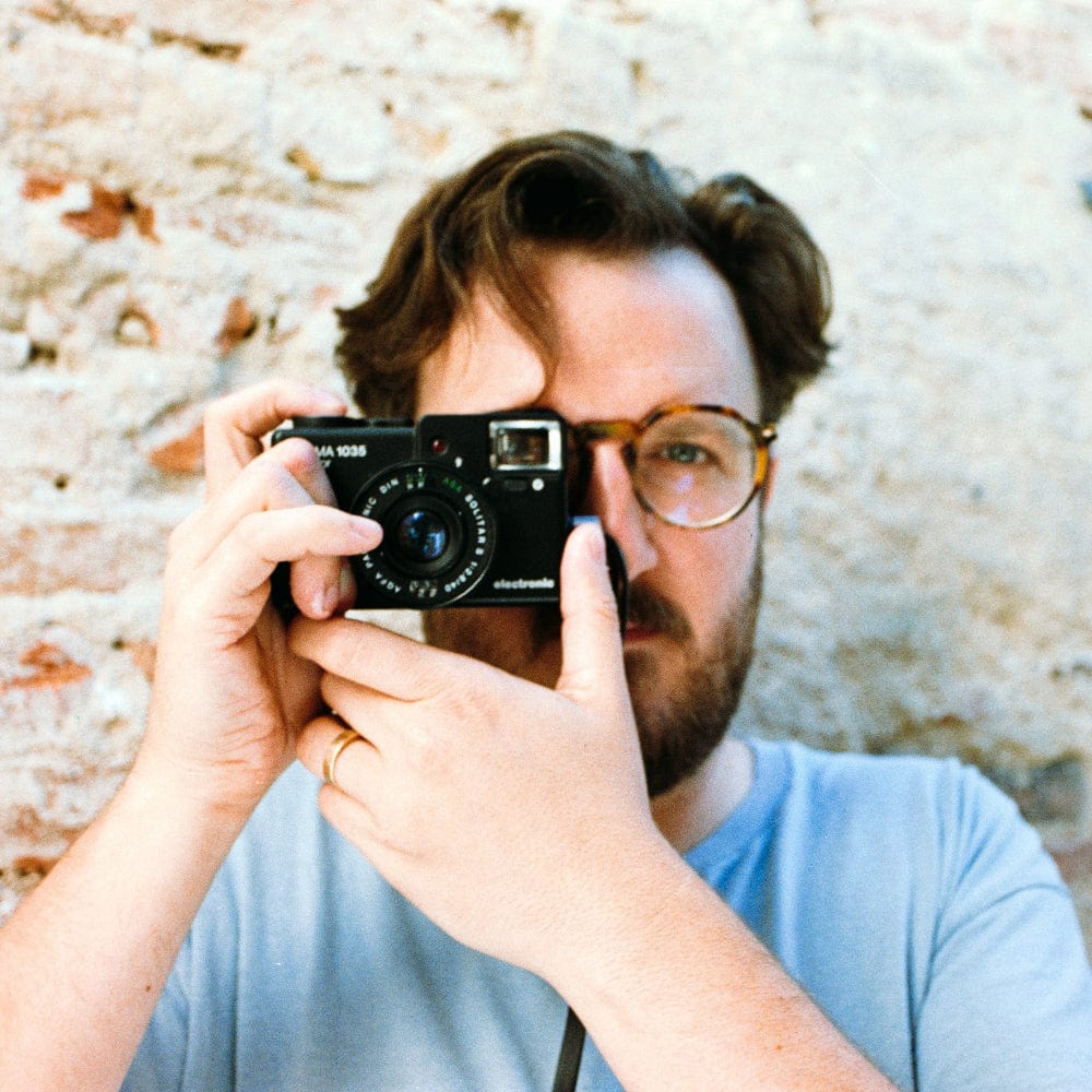 Person holding a camera up to their face with a textured wall background