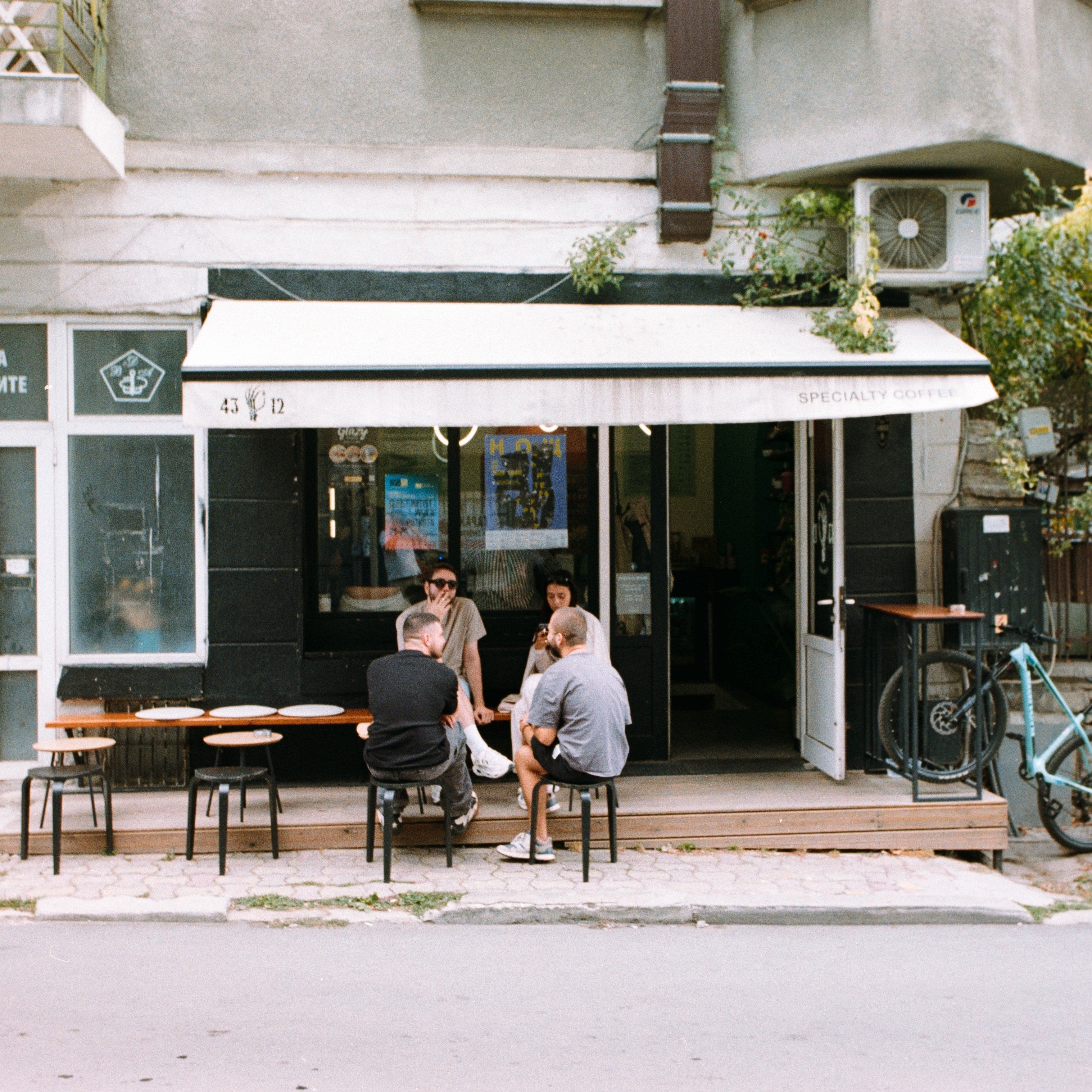 People sitting outside a cafe with a white awning