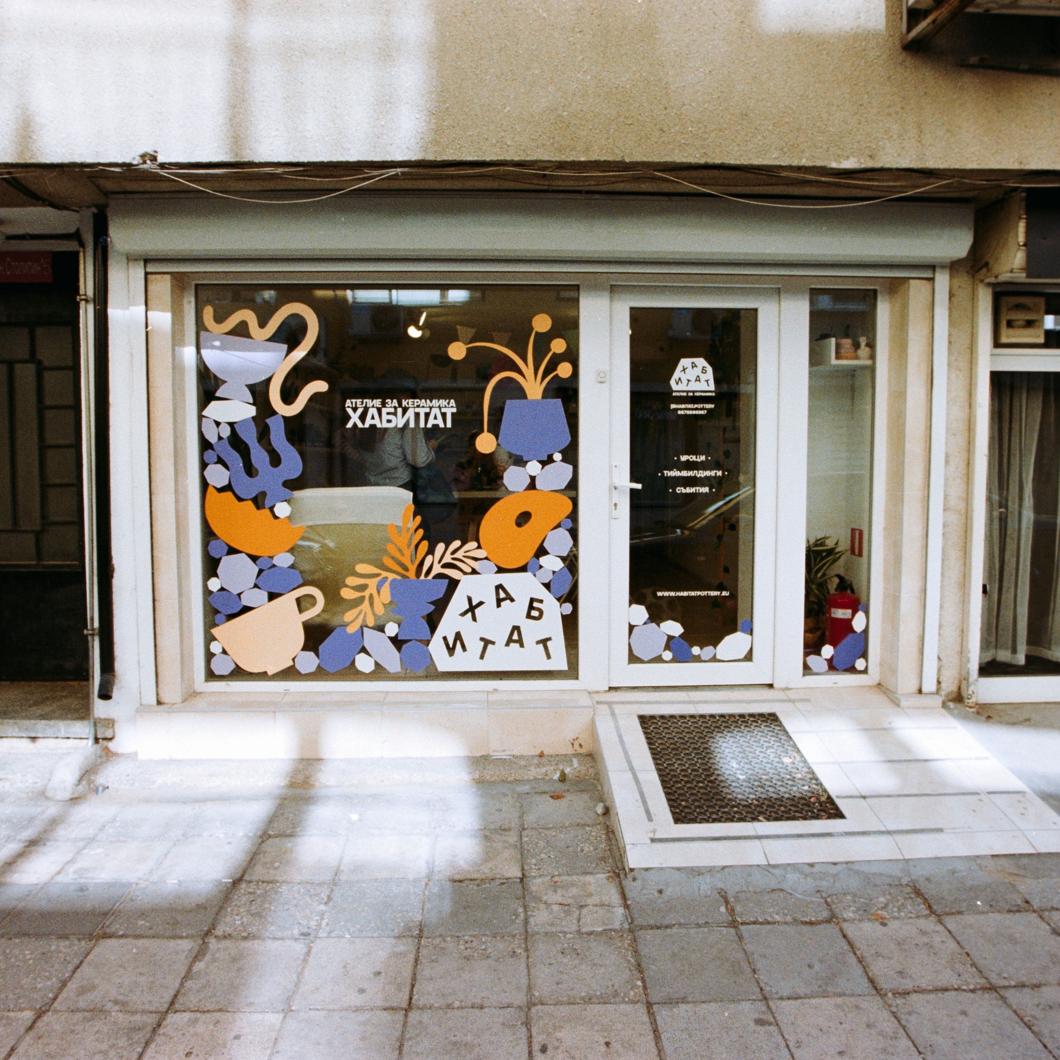 Storefront with decorative window display featuring abstract art and text.
